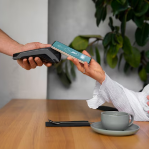 Image of a customer using a smartphone for contactless payment at a restaurant, highlighting safety and convenience.